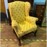 A Victorian wingback armchair, with yellow and red fabric upholstery and studding, raised on