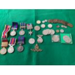 A group of medals relating to the Royal Artillery with a cap badge and some loose coins. The