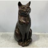 A modern cold cast copper seated black cat with tail curled around its feet by Peter Close,