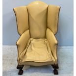 A large Victorian wingback armchair upholstered in cream leather with studding to top, sides and