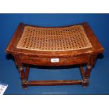 A wood and rattan foot stool with scroll ends, 18 1/2" wide x 12" deep x 12" tall.