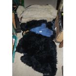 Two black sheepskin rugs and a sheepskin coat.