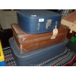 Three vintage suitcases; two blue and one brown.