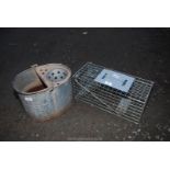 A vermin trap and galvanised mop bucket.