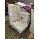 A low Edwardian nursing Chair having turned front legs and upholstered in cream ground floral
