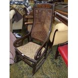 An unusual ebonised framed Rocking Chair having a caned seat and backrest,
