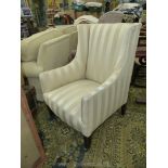 An elegant Edwardian wing fireside Chair upholstered in alternating matt and satin beige striped