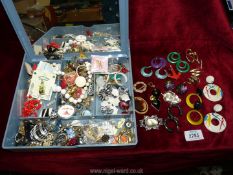 An Estee Lauder gift box with a quantity of costume jewellery to include; earrings, pin badges,