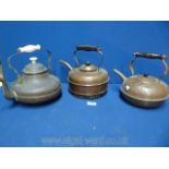 Three copper kettles including one with a porcelain handle.