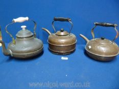 Three copper kettles including one with a porcelain handle.