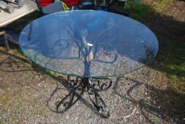 A wrought iron based table with glass top, 39" diameter.
