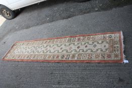 A fringed carpet runner in cream orange and green, 105'' x 26''.