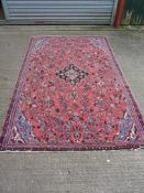 A large rug in pink and blue with central diamond and floral pattern, 99'' x 63''.