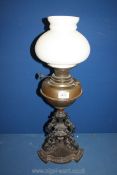 An ornate oil lamp with cast metal base, single burner, white glass shade but no chimney, 24'' tall.