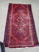 A small woollen rug in red and blue with border pattern, wear to the centre, 74'' x 42''.