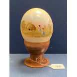 A painted Ostrich egg on wooden holder.