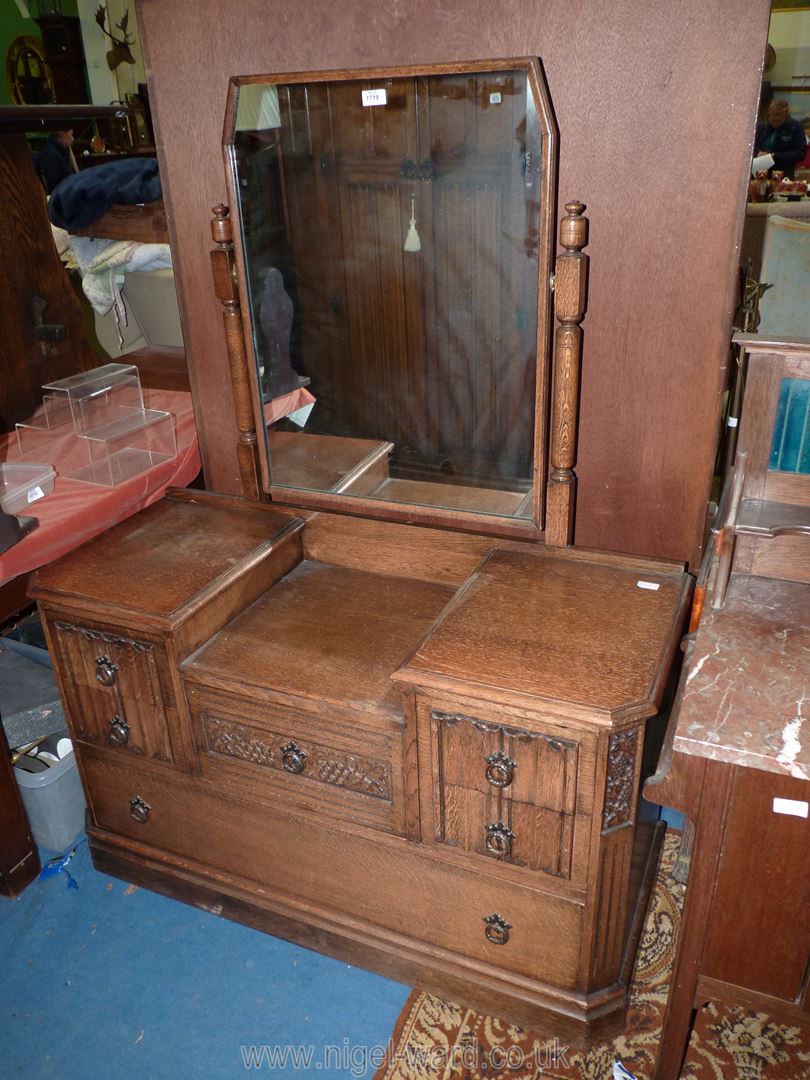 An Oak dressing Table having linen fold and fruiting vine detail and shaped swing mirror,