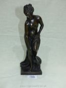 A bronze figure of Aphrodite standing naked with her robe draped over one leg, 10 1/2" tall.