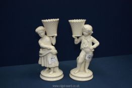 A pair of Belleek creamware spill vases of a boy and a girl, 9'' tall.