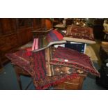 A quantity of textiles including carpet cushions, saddle bag, etc.
