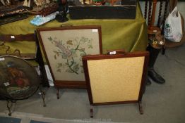 A wooden framed fire screen covered in a yellow fabric and a wooden framed and glass fire screen