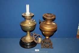 A brass oil lamp on black plinth converted to electric, plus another brass oil lamp (no shade).