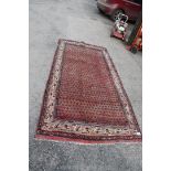 A Persian Sarouk runner, washed red ground, Mir design, 2.55m x 1.28m.