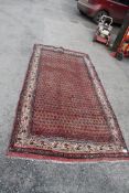 A Persian Sarouk runner, washed red ground, Mir design, 2.55m x 1.28m.