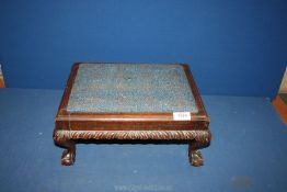 A wooden footstool having blue upholstered seat, some damage.