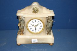 An Alabaster mantle clock flanked by two spelter style figures,