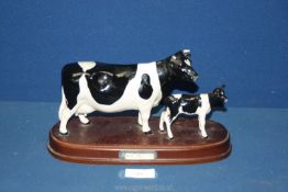 A Beswick Friesian Cow and Calf on wooden plinth.