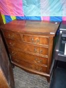 A contemporary Walnut and Mahogany bow fronted Chest of three long and two short drawers having