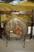 A brass framed firescreen with oval panel, centre having a picture of a galleon.