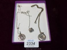 Two silver St Christopher pendants with chains and a silver locket with chain.