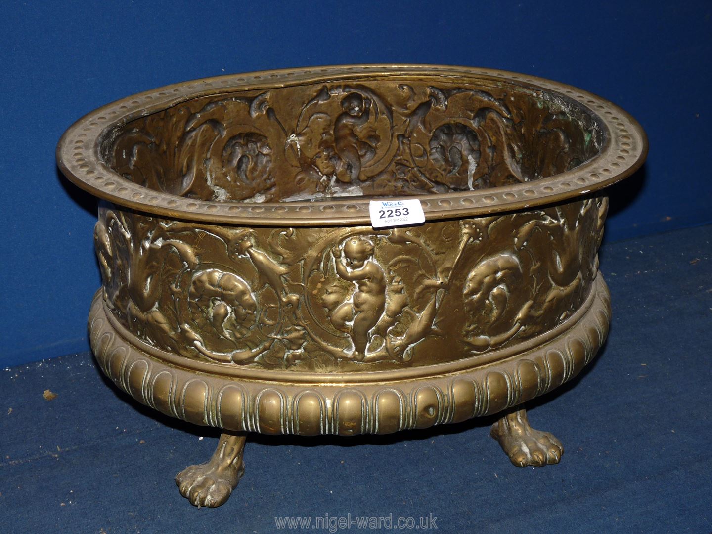 A brass Jardiniere with images in relief, standing on paw feet, 20'' x 16'' x 11'' tall.
