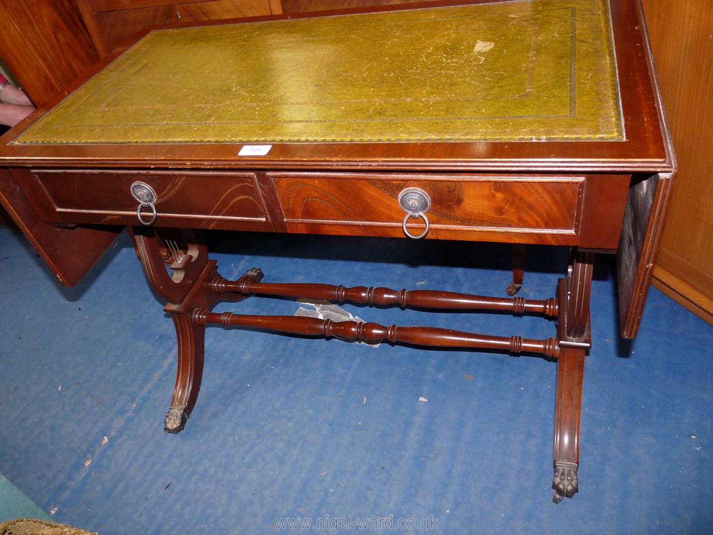 A drop leaf writing desk with lyre sides and green leather inserts, on casters, 57'' x 20'' x 29''.