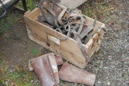 A wooden crate of old horse tack and leather gaiters.