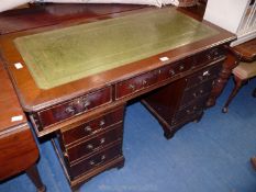 A dark wood kneehole writing desk with green tooled leather insert, 48'' wide x 31'' high.
