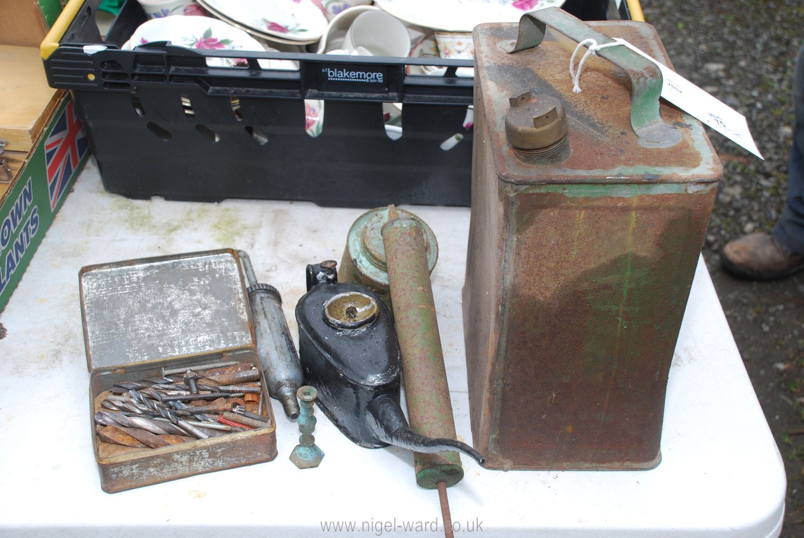 A fuel can, oil can, grease gun and drill bits.