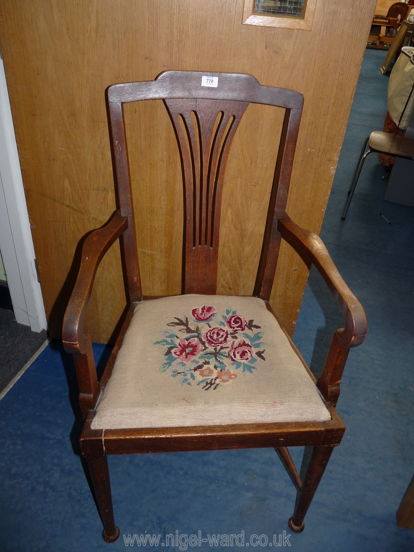 A dark-wood hall carver chair with tapestry seat.