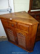 An Indian Redwood corner display cabinet with three drawers and fret-work door fronts.