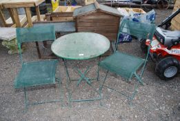 A circular metal bistro table and two metal and canvas chairs.
