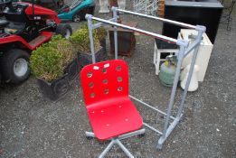 A red MDF swivel chair and a plastic wheeled clothes rail.