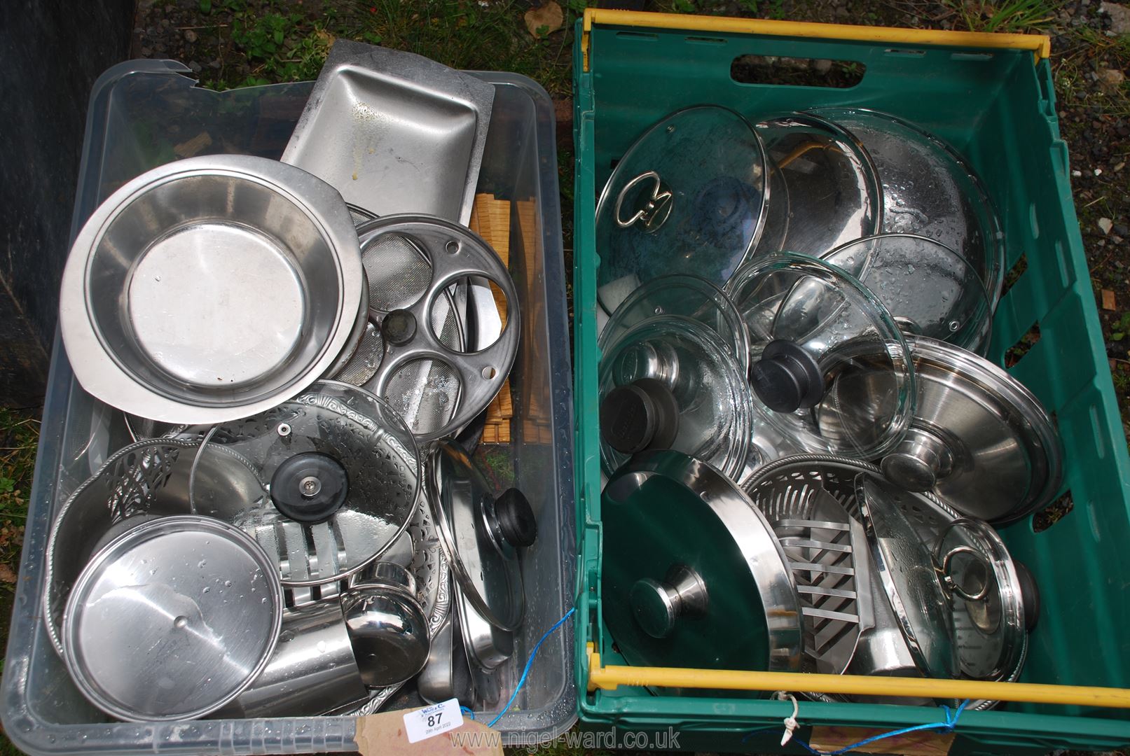 Two plastic crates of stainless steel cookware.