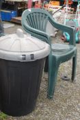 A plastic dustbin and two green plastic chairs