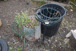 A dustbin, galvanised bin with plants and two basket holders.