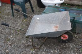 A galvanised wheelbarrow with solid wheel.