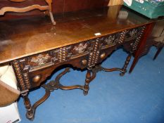 A dark-wood carved front side table with two drawers and curved stretcher base 50" W.