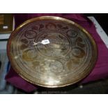 A round Indian solid polished brass tray decorated with dancing figures, foliage and animals,