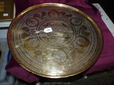 A round Indian solid polished brass tray decorated with dancing figures, foliage and animals,